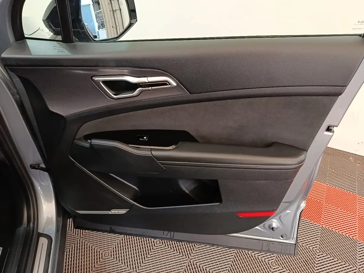 Vue intérieure de la porte côté conducteur gris clair du Kia Sportage 2022 avec garniture noire et haut-parleur Harman Kardon.
