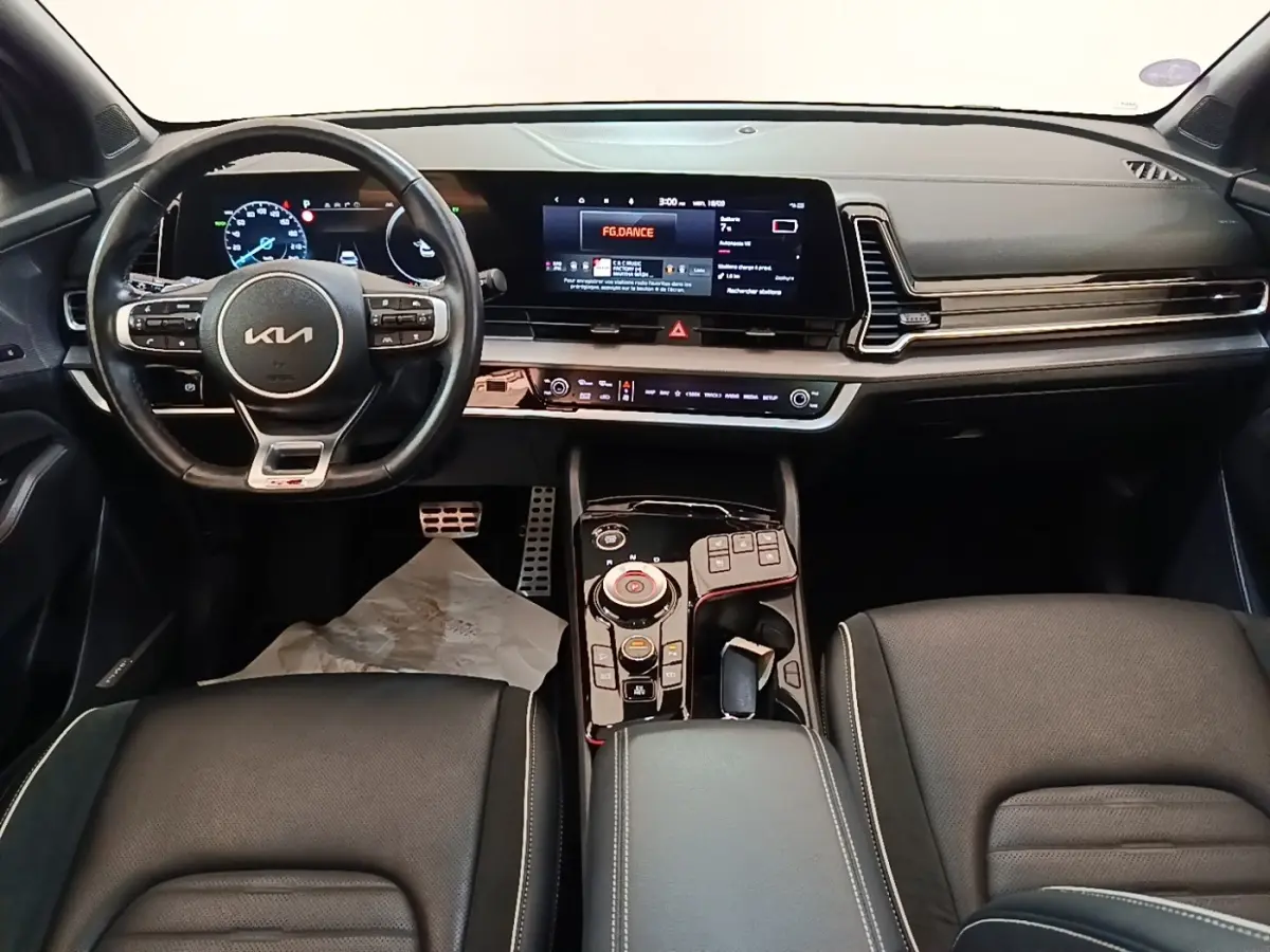 Vue intérieure avant du tableau de bord et volant noir du Kia Sportage hybride rechargeable 2022 avec écran tactile large.