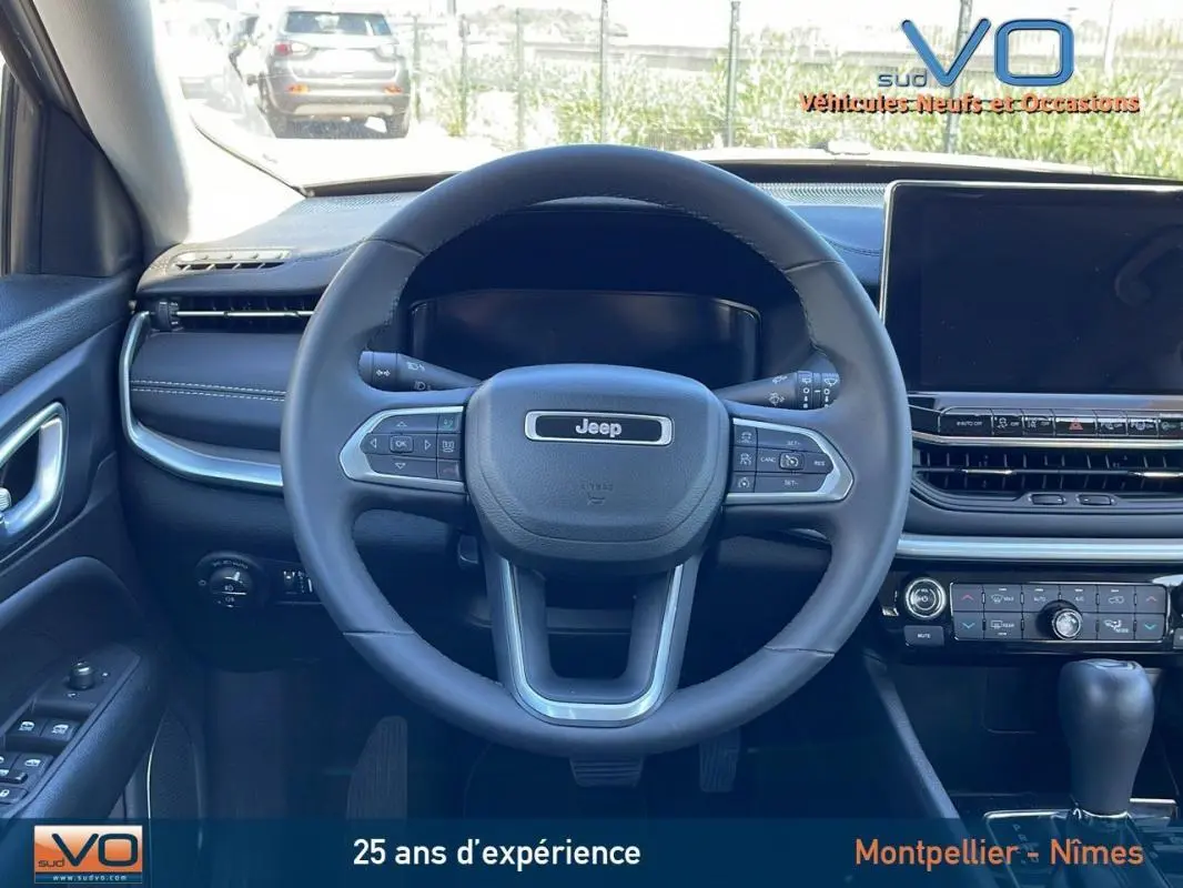 Vue intérieure centrée sur le volant Jeep Compass 2024, tableau de bord noir avec écran tactile et commandes intégrées.