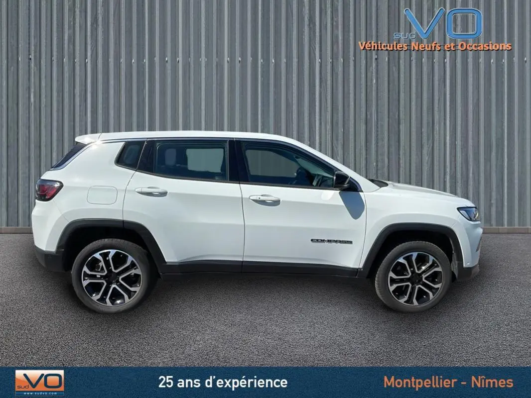 Profil côté gauche d'un Jeep Compass blanc 2024 avec jantes alliage 18 pouces sur fond urbain.