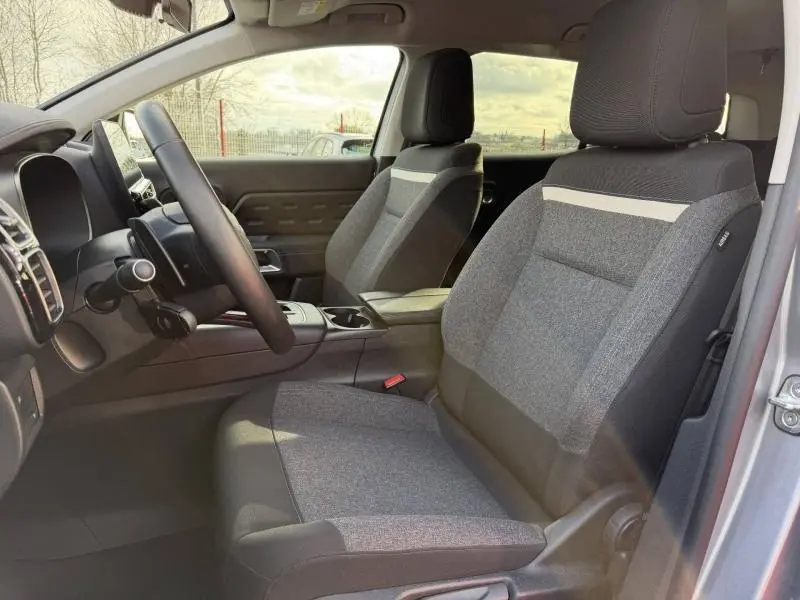 Vue intérieure côté conducteur du Citroën C5 Aircross gris 2024, mettant en valeur les sièges tissu bicolore et la console centrale.