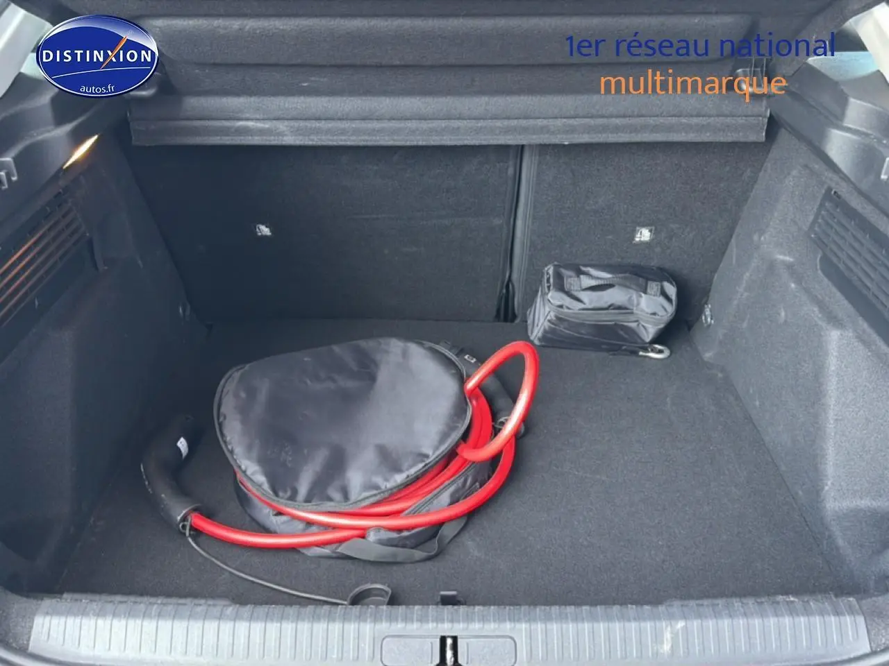 Coffre ouvert vu de face d'une Citroën C4 électrique gris foncé avec câble de recharge rouge rangé à l'intérieur.