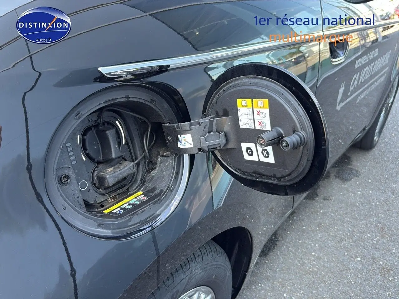 Détail de la trappe de recharge ouverte côté gauche d’une Fiat 500 électrique blanche, vue rapprochée.