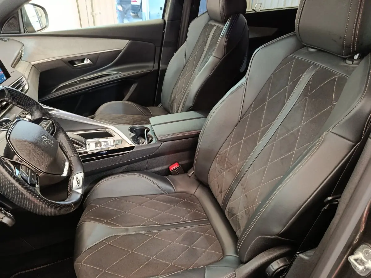 Vue intérieure côté conducteur du Peugeot 5008 gris clair, avec sièges en cuir et alcantara, volant multifonctions.