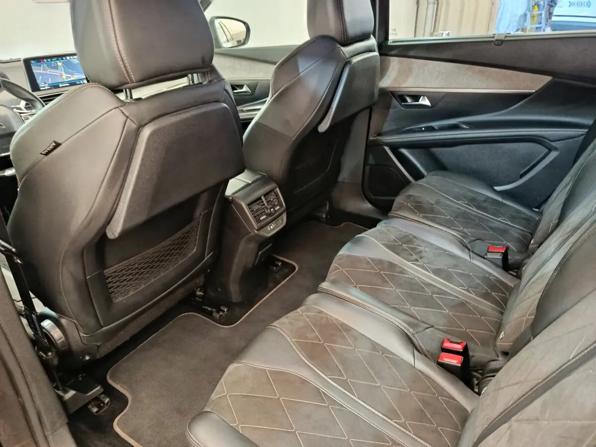 Vue intérieure arrière côté droit du Peugeot 5008 gris clair, montrant les sièges en cuir et alcantara avec coutures apparentes.