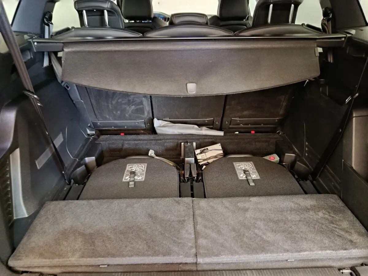 Vue du coffre arrière du Peugeot 5008 gris clair, montrant les sièges arrière rabattus et la tablette cache-bagages déployée.
