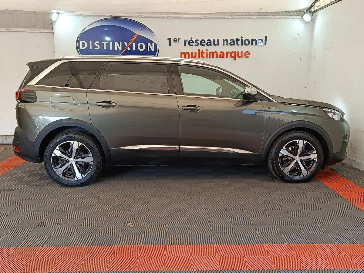 Peugeot 5008 gris clair vue de profil côté gauche, avec jantes alliage et toit noir contrasté.
