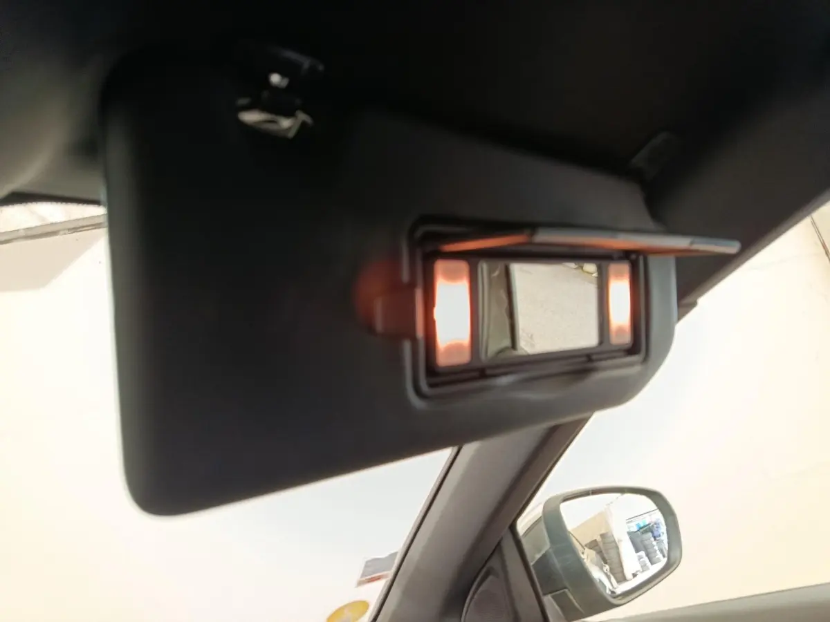Miroir de courtoisie éclairé sur pare-soleil côté conducteur dans Peugeot 5008 gris clair, vue intérieure rapprochée.