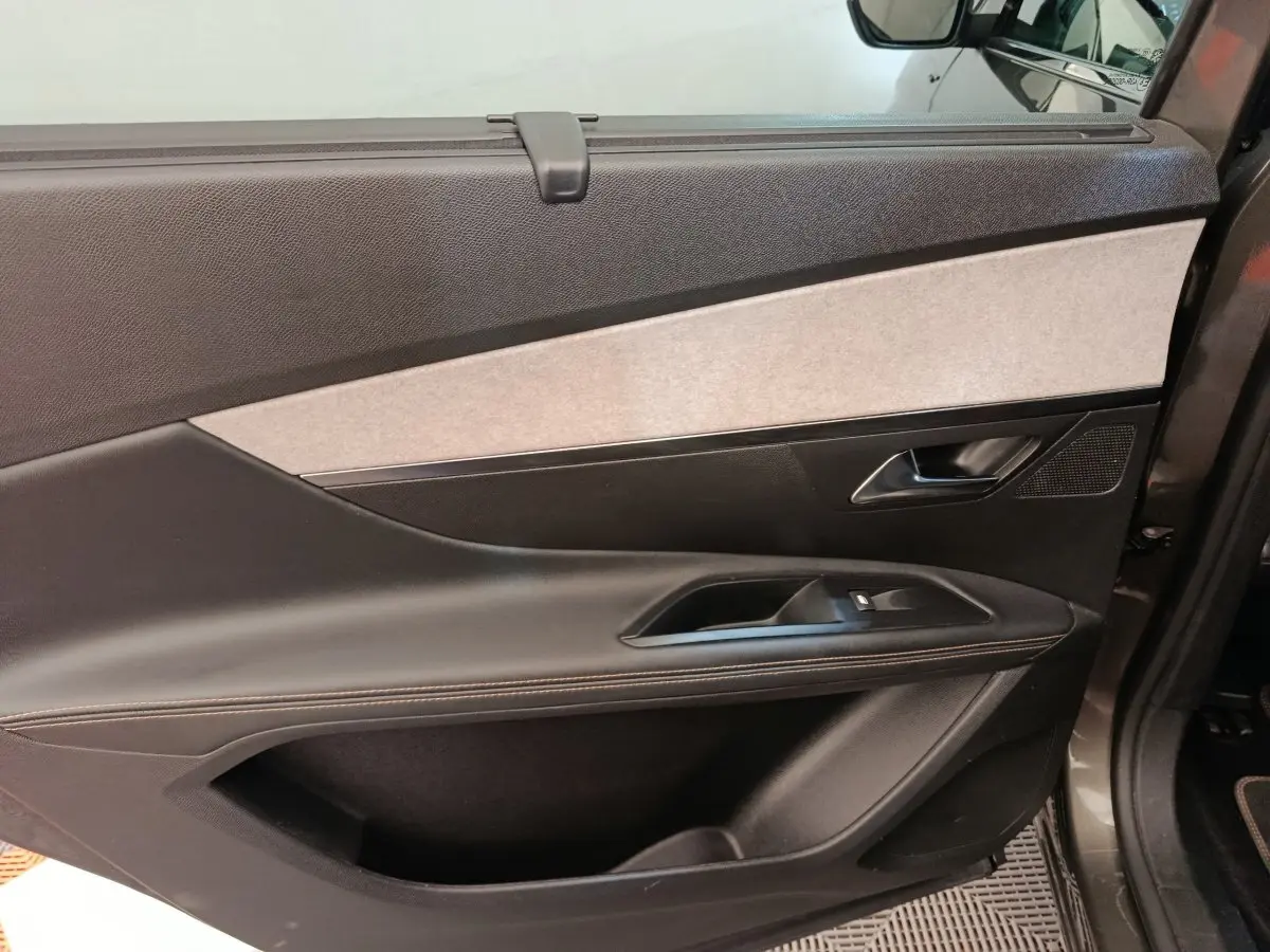Vue intérieure de la porte avant droite du Peugeot 5008 gris clair, avec garniture noire et insert gris clair.