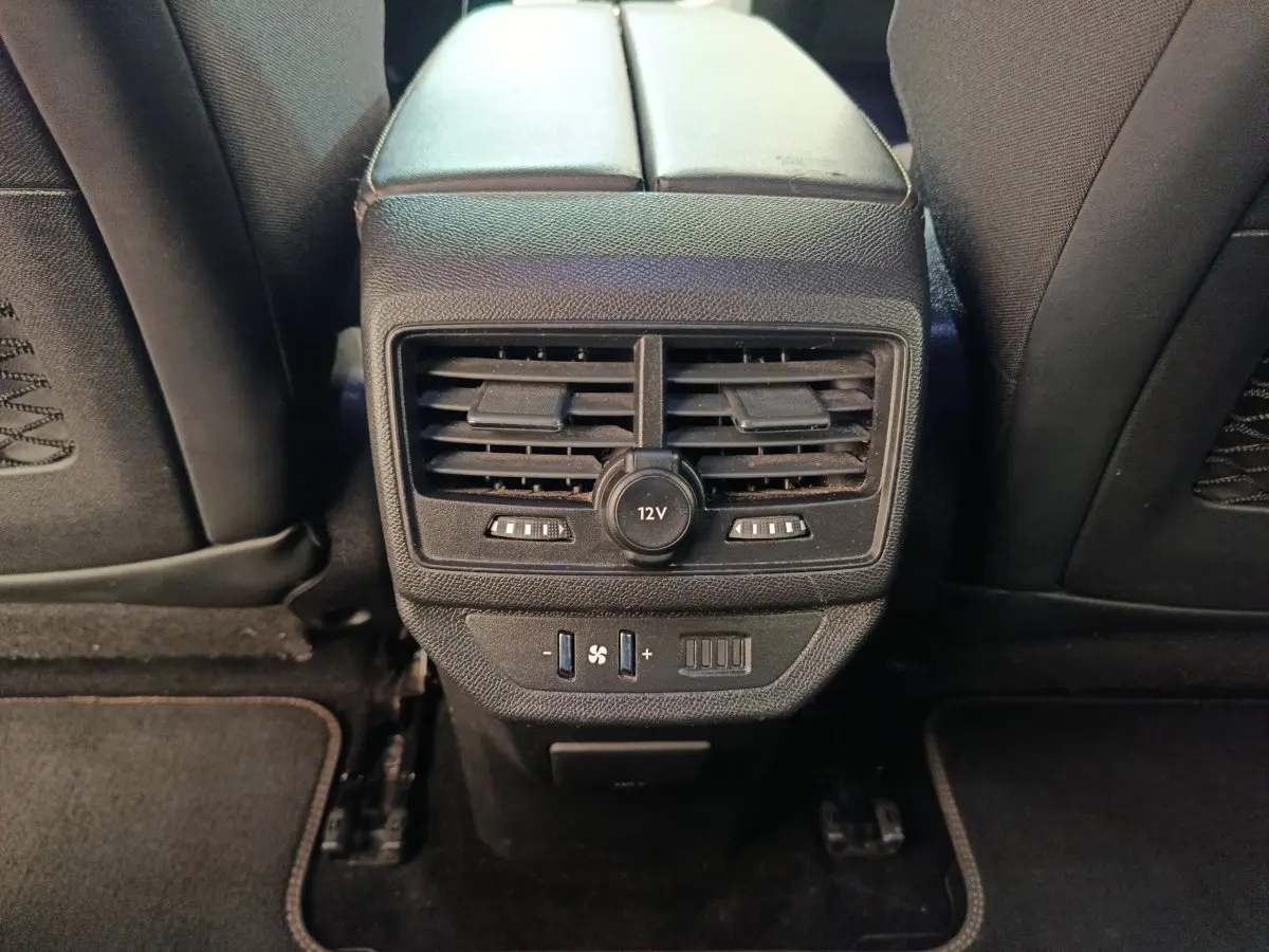 Vue rapprochée de la console centrale arrière noire avec aérateurs et prise 12V du Peugeot 5008 gris clair.
