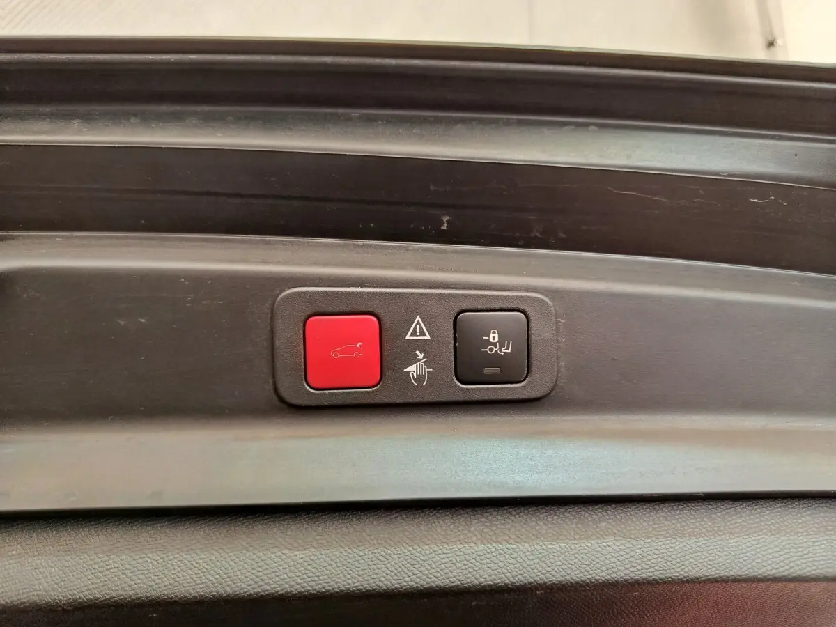 Gros plan sur les boutons de commande du coffre électrique, intérieur noir du Peugeot 5008 gris clair.