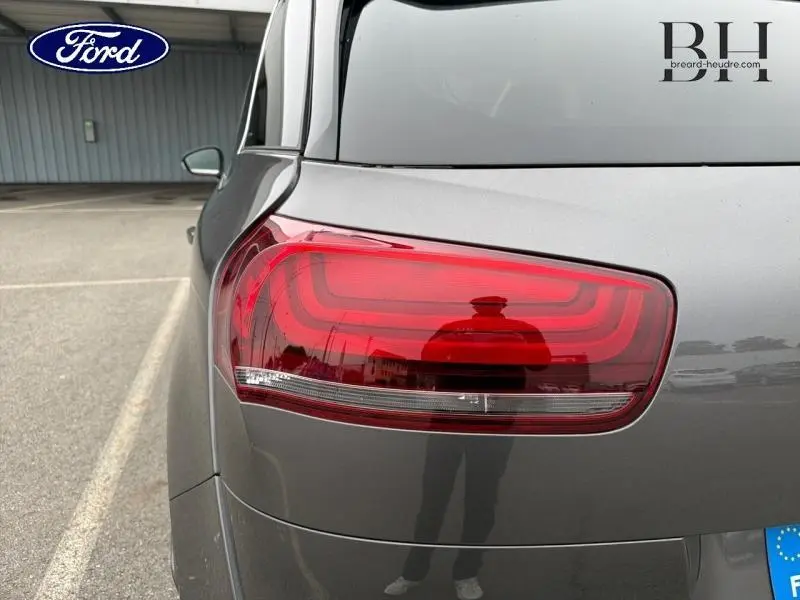 Gros plan sur le feu arrière gauche d'une Citroën C4 Spacetourer gris Platinium, avec reflet sur la carrosserie.