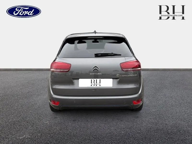 Vue arrière d'une Citroën C4 Spacetourer gris Platinium avec feux rouges et lunette arrière surteintée.