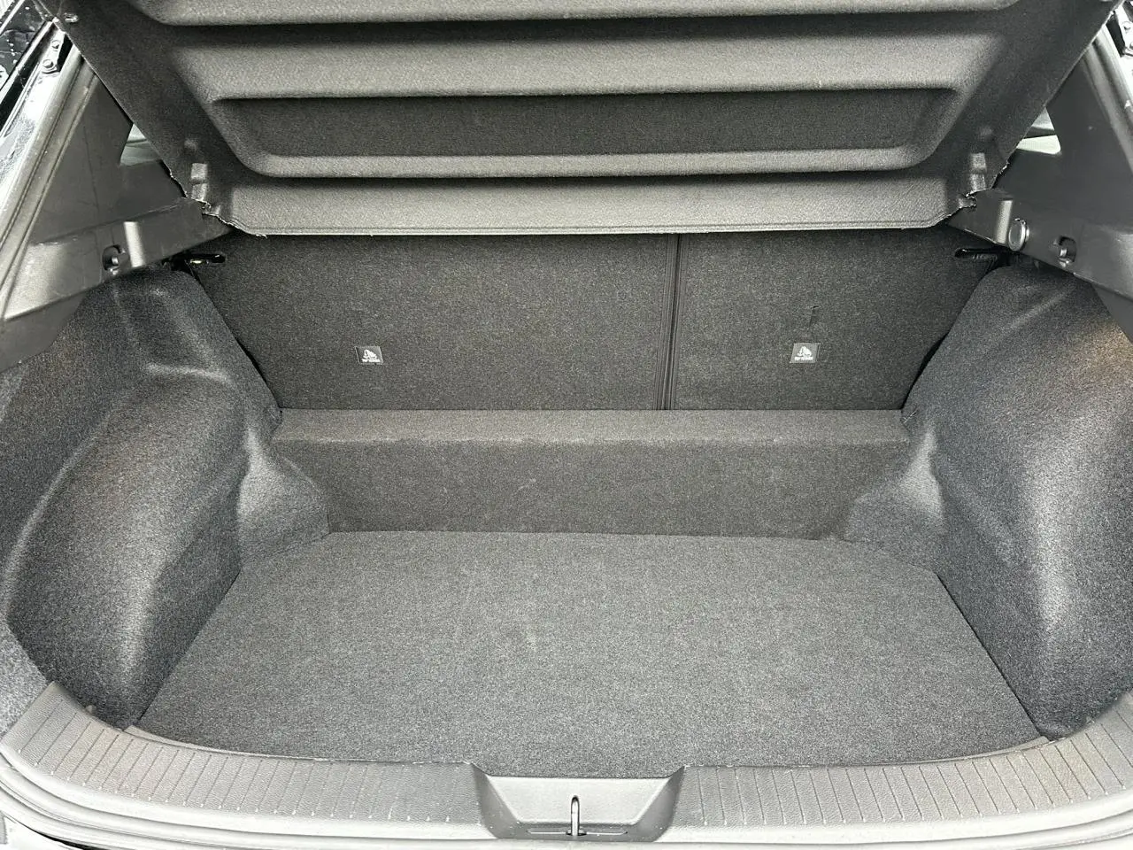 Coffre ouvert du Nissan Qashqai noir nacré, vue intérieure montrant l’espace de chargement vide et la moquette grise.