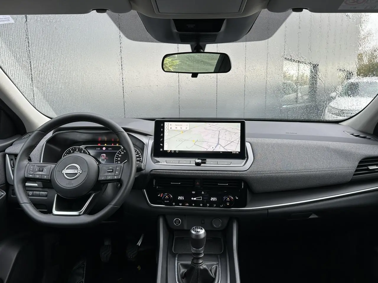 Vue intérieure avant du Nissan Qashqai 2025 noir nacré, avec volant multifonction, écran tactile et boîte manuelle.