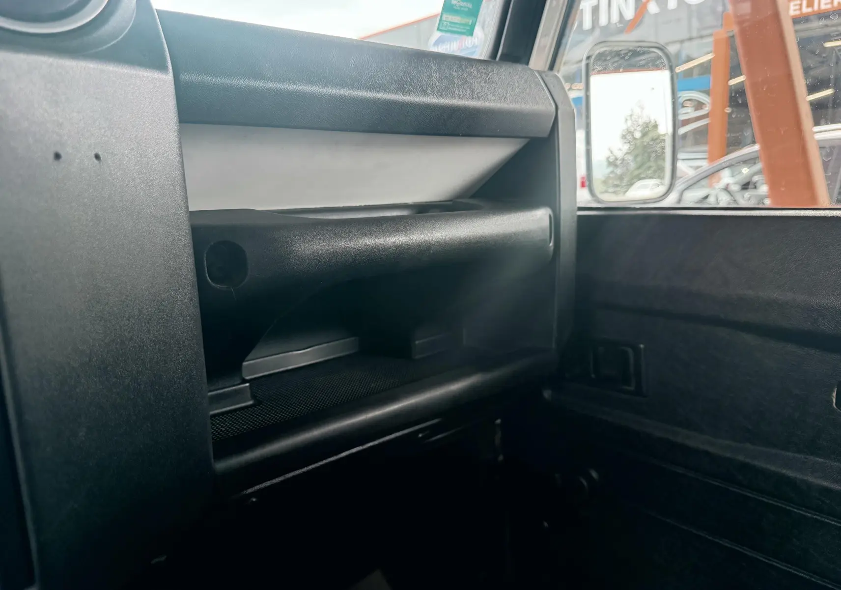 Détail de la boîte à gants et de la portière côté passager intérieur du Land Rover Defender blanc de 2007.