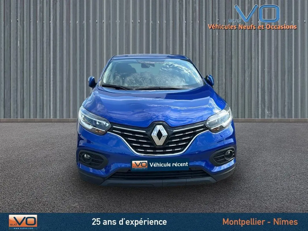 Vue frontale d'un Renault Kadjar TCe 140 bleu foncé avec phares allumés et calandre chromée visible.