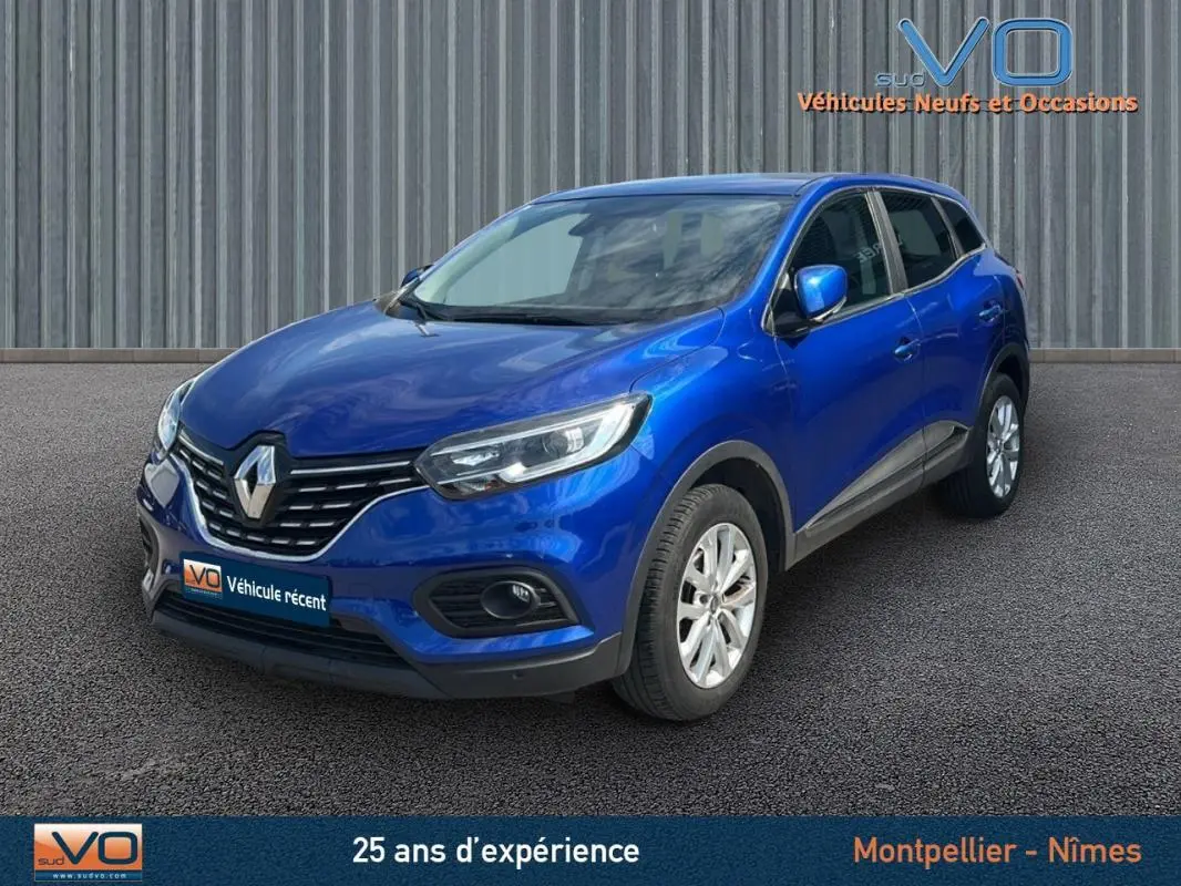 Renault Kadjar TCe 140 bleu foncé vu en 3/4 avant droit avec jantes alliage et barres de toit visibles.