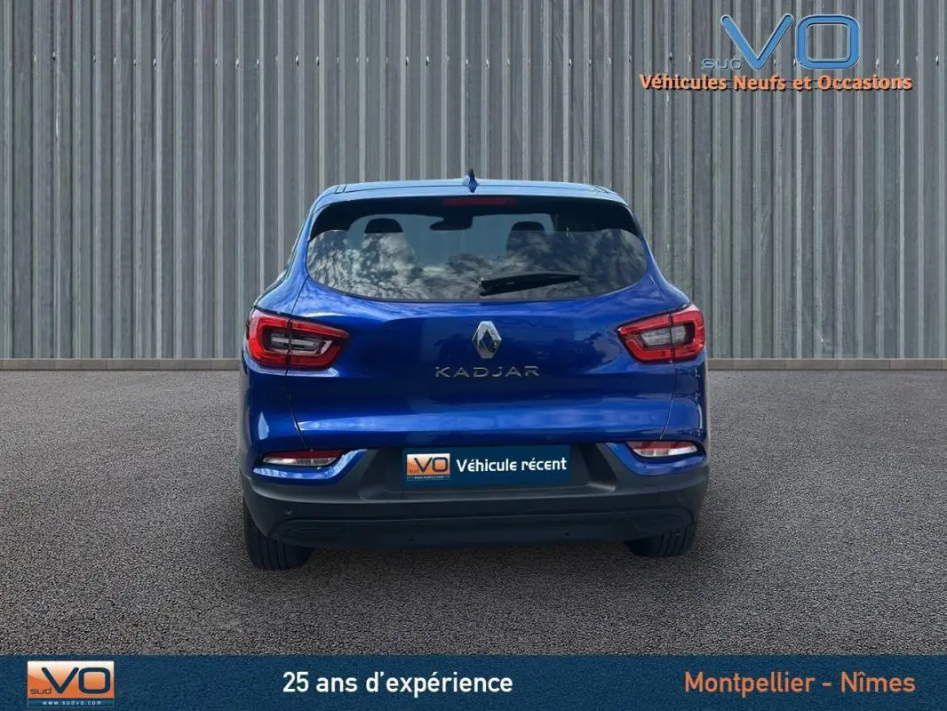 Vue arrière d'un Renault Kadjar bleu foncé 2021 avec feux LED et hayon fermé sur fond industriel.