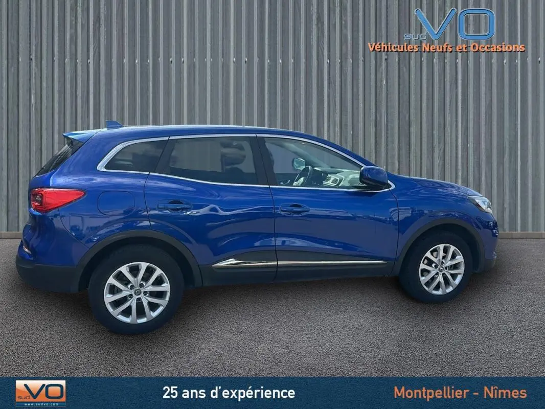 Profil côté gauche d'un Renault Kadjar TCe 140 FAP Business bleu foncé avec jantes alliage 17 pouces sur fond urbain.
