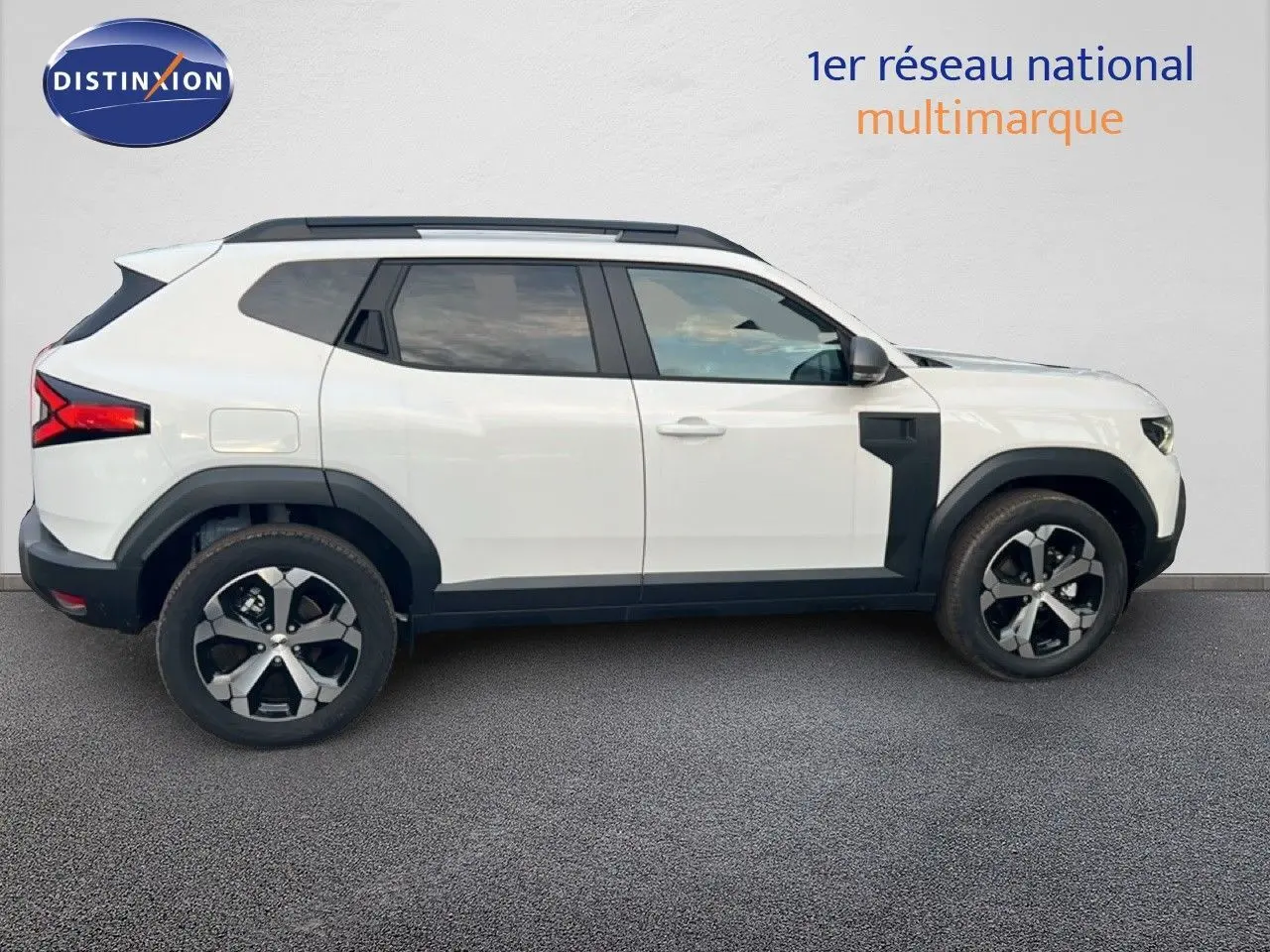 Profil droit du Dacia Duster blanc glacier 2025 avec jantes bi-ton et protections noires contrastantes.