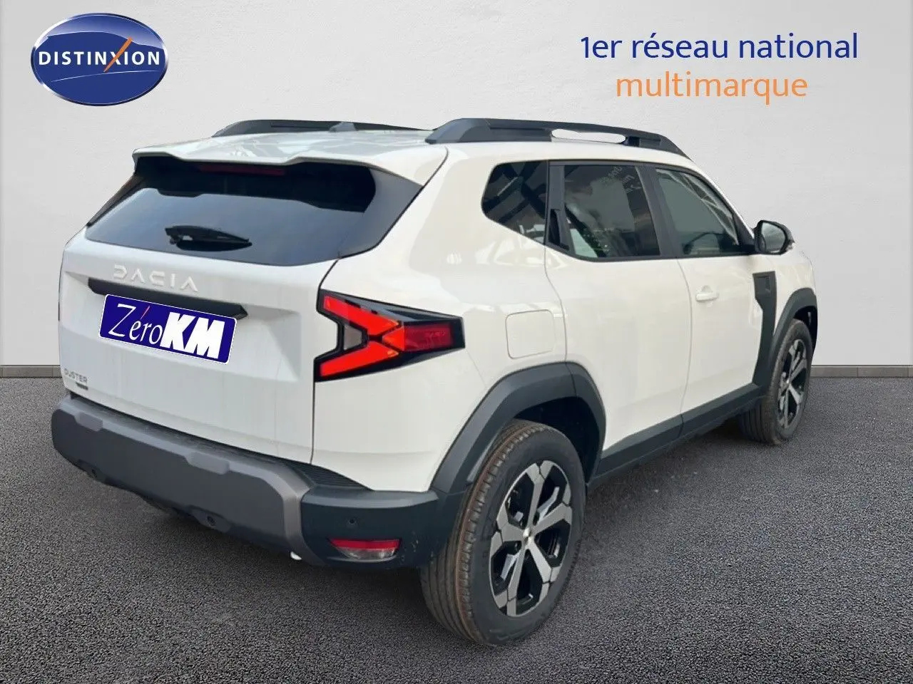 Vue 3/4 arrière droite du Dacia Duster blanc glacier 2025 avec jantes bi-ton et protections noires contrastantes.