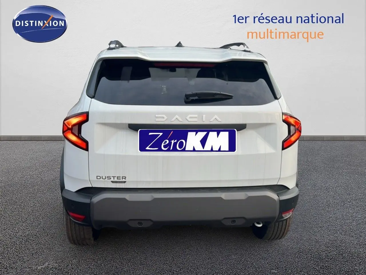 Vue arrière d'un Dacia Duster blanc glacier 2025 avec feux arrière allumés et plaque Zéro KM visible.