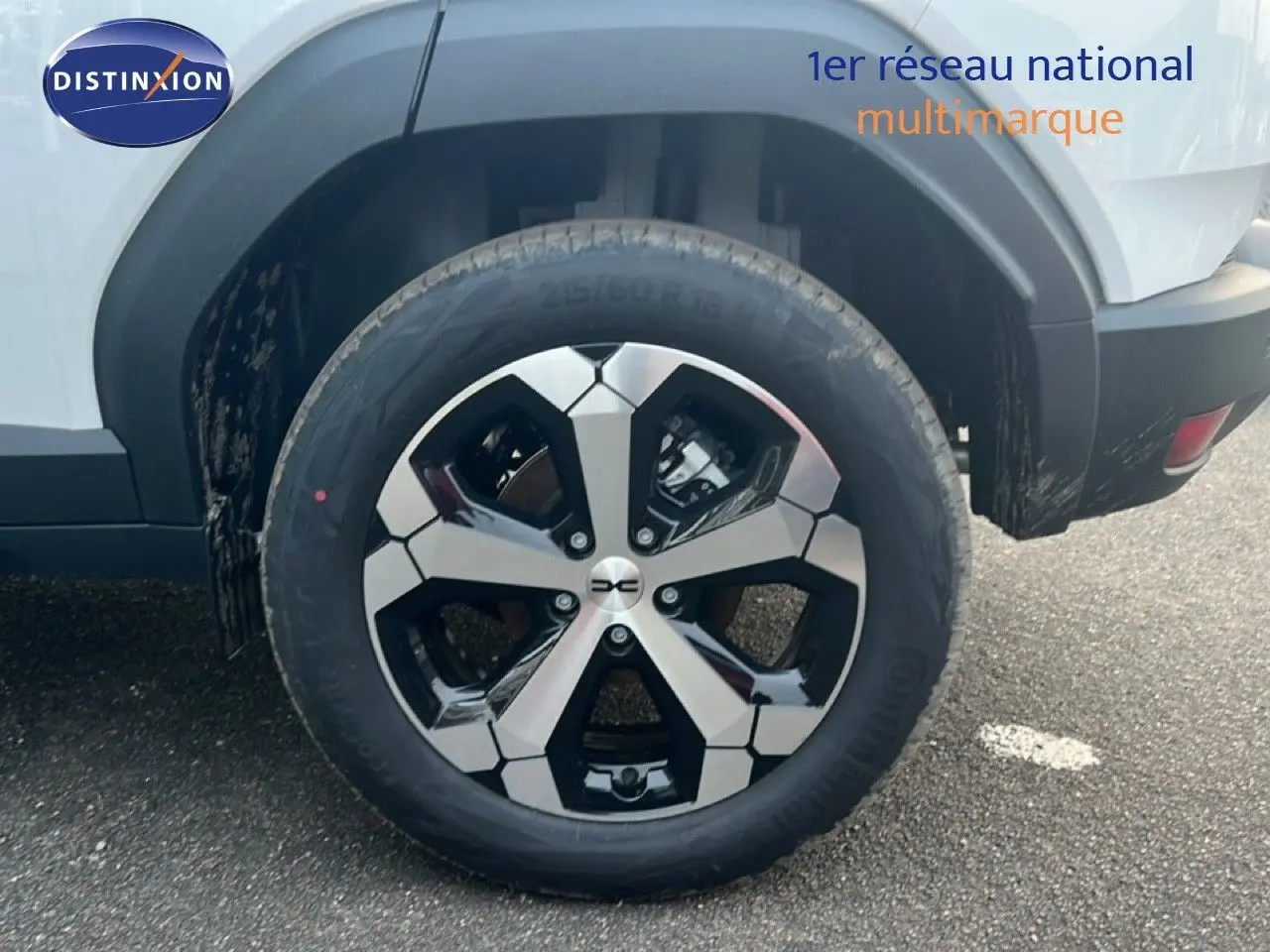 Gros plan sur la roue arrière droite du Dacia Duster blanc glacier 2025 avec jante alliage bicolore distinctive.