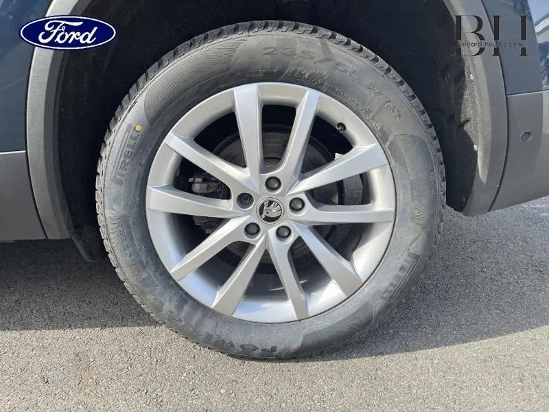 Gros plan sur la roue avant droite d'un Skoda Kodiaq bleu lave métallisé avec jante alliage argentée à 5 doubles branches.