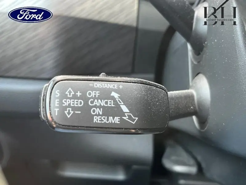 Levier de commande du régulateur de vitesse sur un volant de Ford, vue rapprochée côté gauche, intérieur noir.