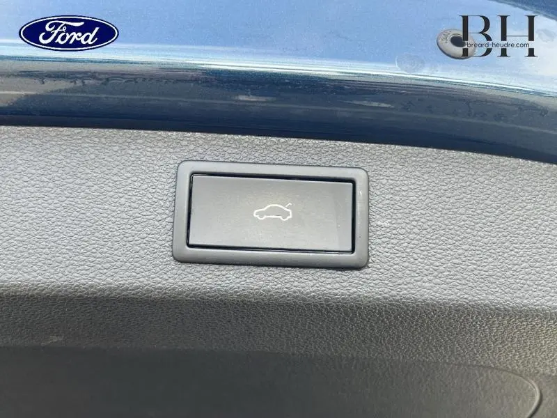 Bouton d'ouverture électrique du coffre sur la partie intérieure d'un Skoda Kodiaq Bleu Lave métallisée, vue rapprochée.