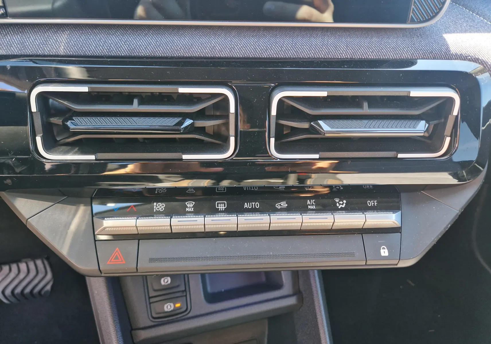 Gros plan sur la console centrale noire du Renault R5 E-TECH 2025, montrant les aérateurs et commandes climatisation.