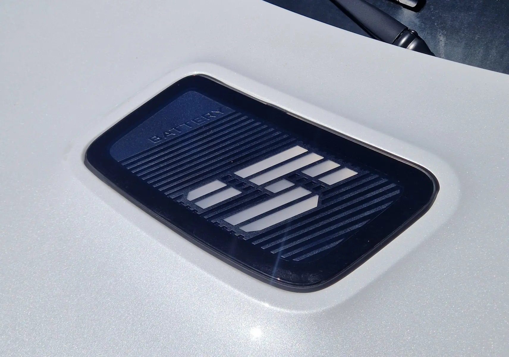 Gros plan sur l’inscription "BATTERY" sur la carrosserie blanc nacré de la Renault R5 E-TECH TECHNO 2025.