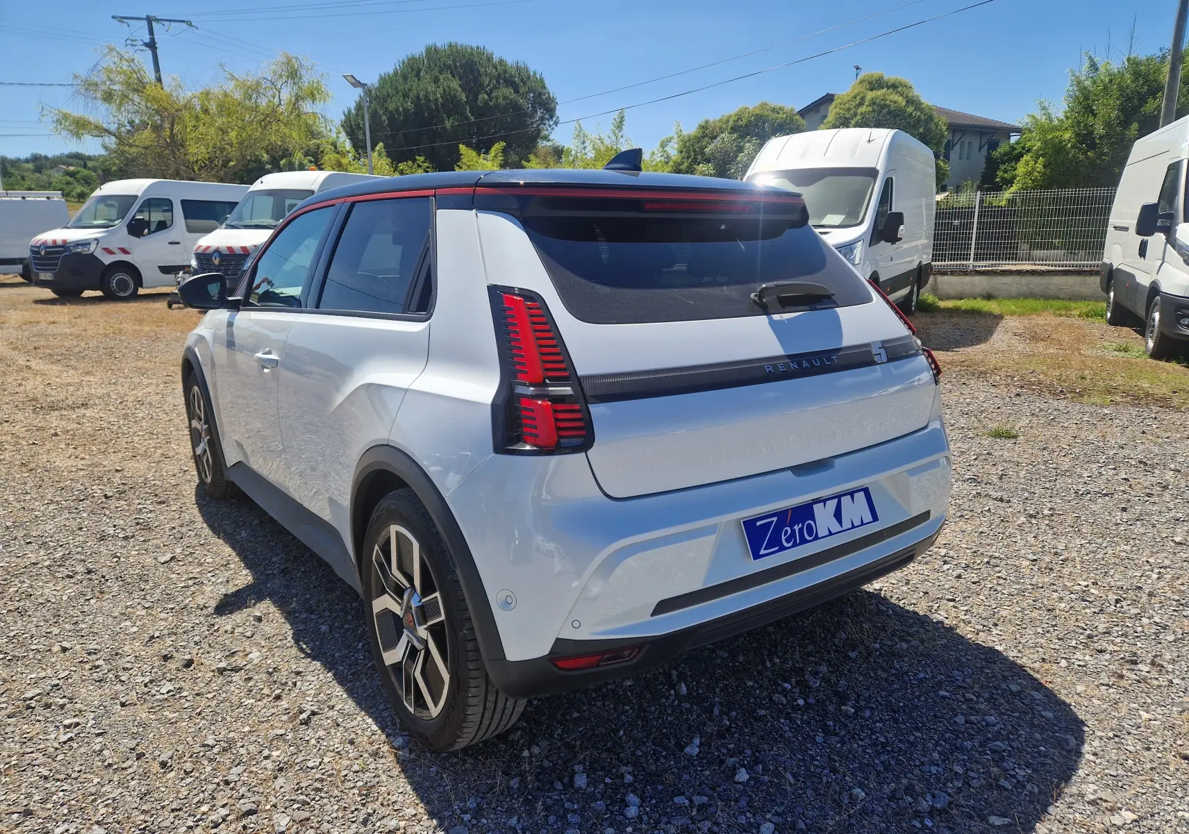 Vue 3/4 arrière droite d'une Renault R5 E-TECH blanc nacré et noir avec feux arrière verticaux distinctifs.