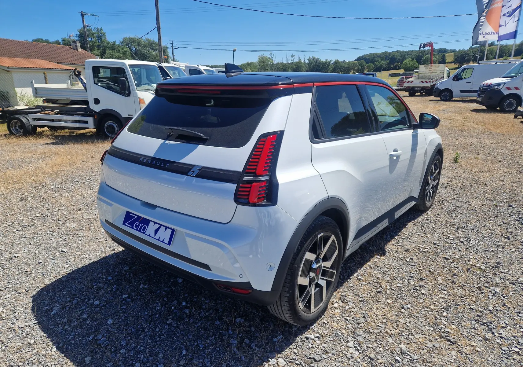Vue 3/4 arrière droite de la Renault R5 E-TECH 2025 blanc nacré avec toit noir et feux arrière LED distinctifs.