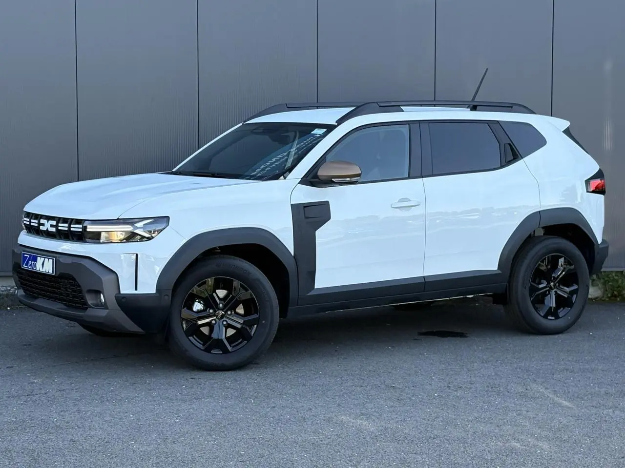 Dacia Duster Blanc Glacier en vue 3/4 avant droit, avec jantes noires et détails noirs contrastants sur les ailes.