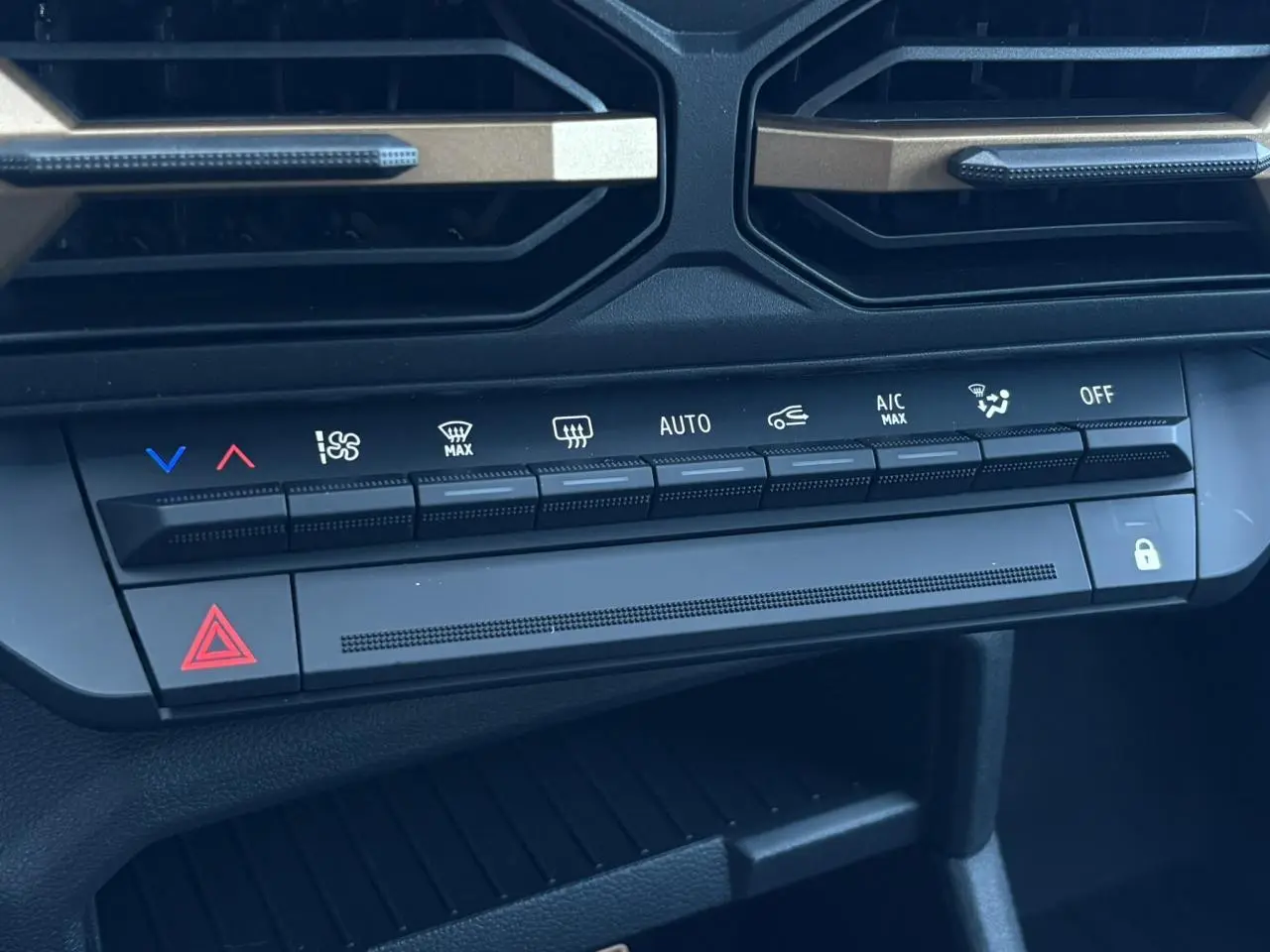 Gros plan sur la console centrale du Dacia Duster blanc Glacier 2026, montrant les commandes de climatisation et sécurité.