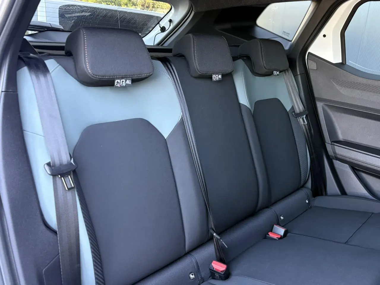 Vue intérieure de la banquette arrière bi-ton noire et grise du Dacia Duster 2026 avec ceintures et appuie-têtes.