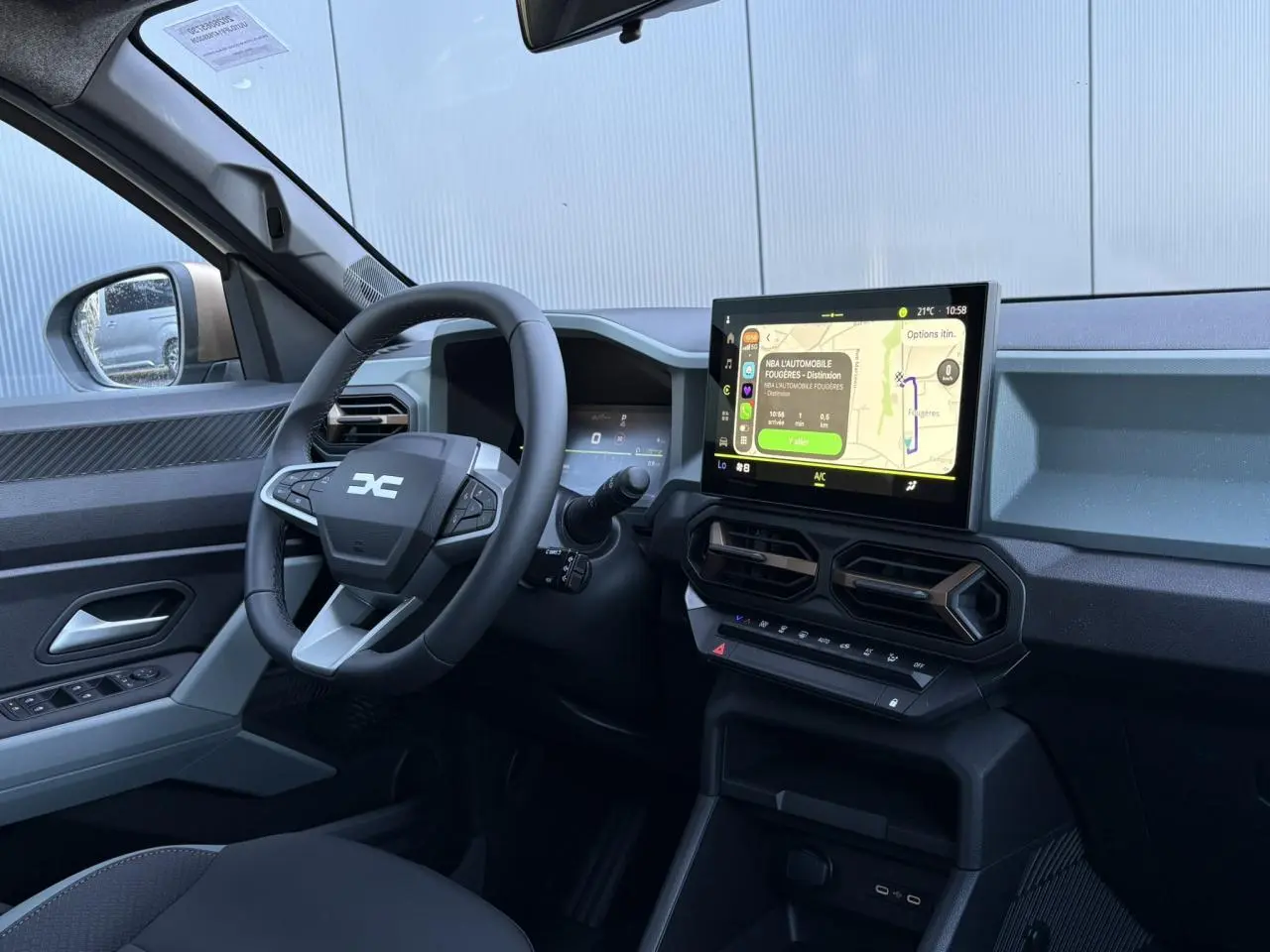 Vue intérieure côté conducteur du Dacia Duster blanc Glacier 2026, tableau de bord digital et écran tactile central visibles.