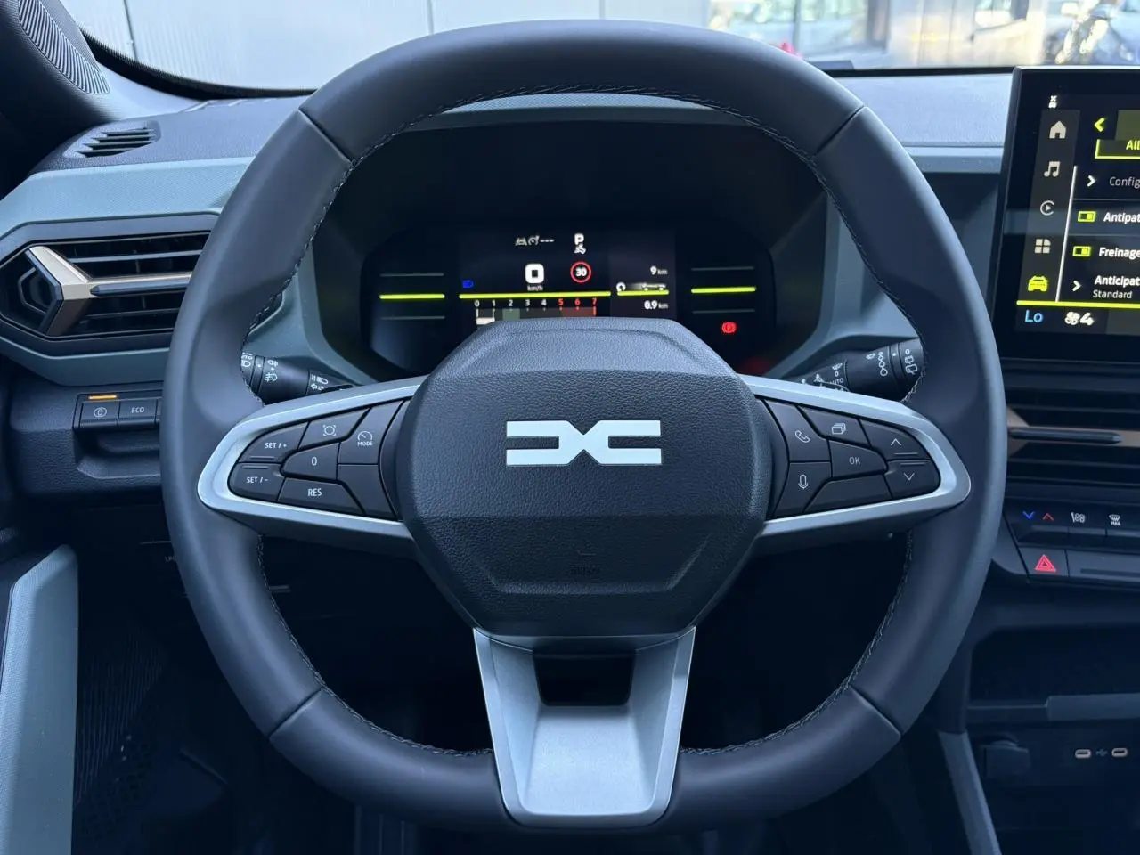 Vue rapprochée du volant noir du Dacia Duster 2026 avec tableau de bord digital et écran tactile central.