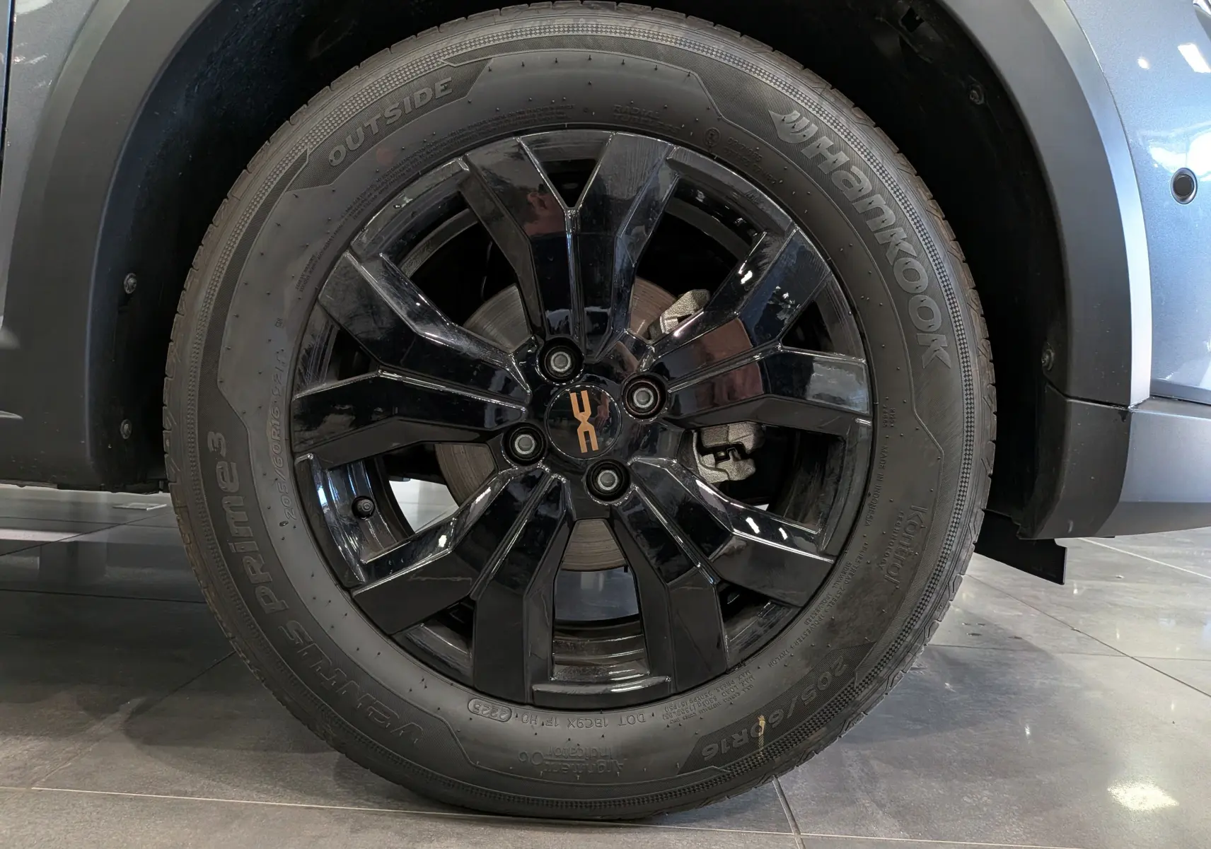 Gros plan sur la roue avant droite noire brillante d'une Dacia Sandero Stepway Gris Schiste 2025, avec logo "X" central.