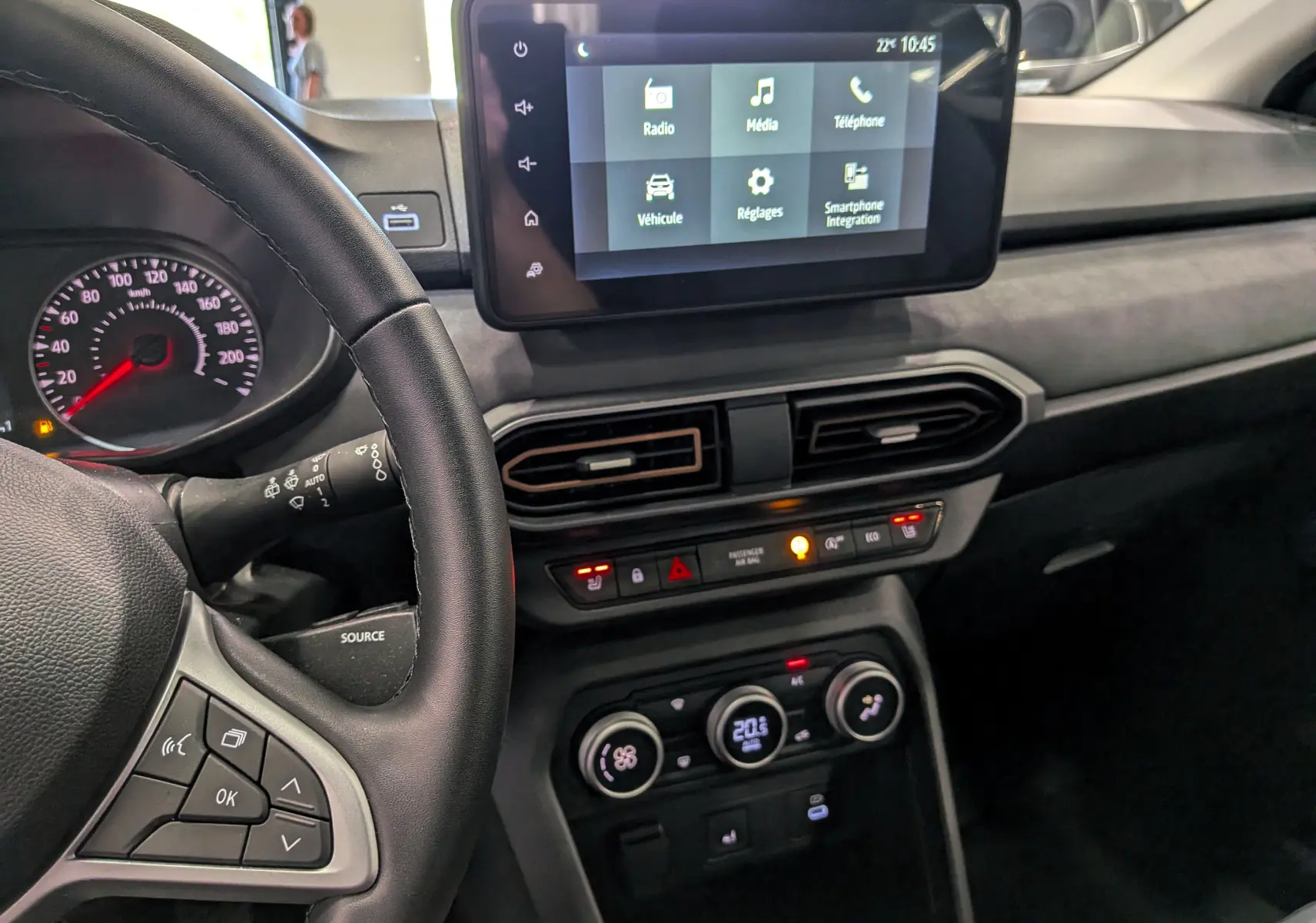 Vue intérieure côté conducteur du tableau de bord gris d'une Dacia Sandero Stepway TCe 110 2025 avec écran tactile et commandes au volant.