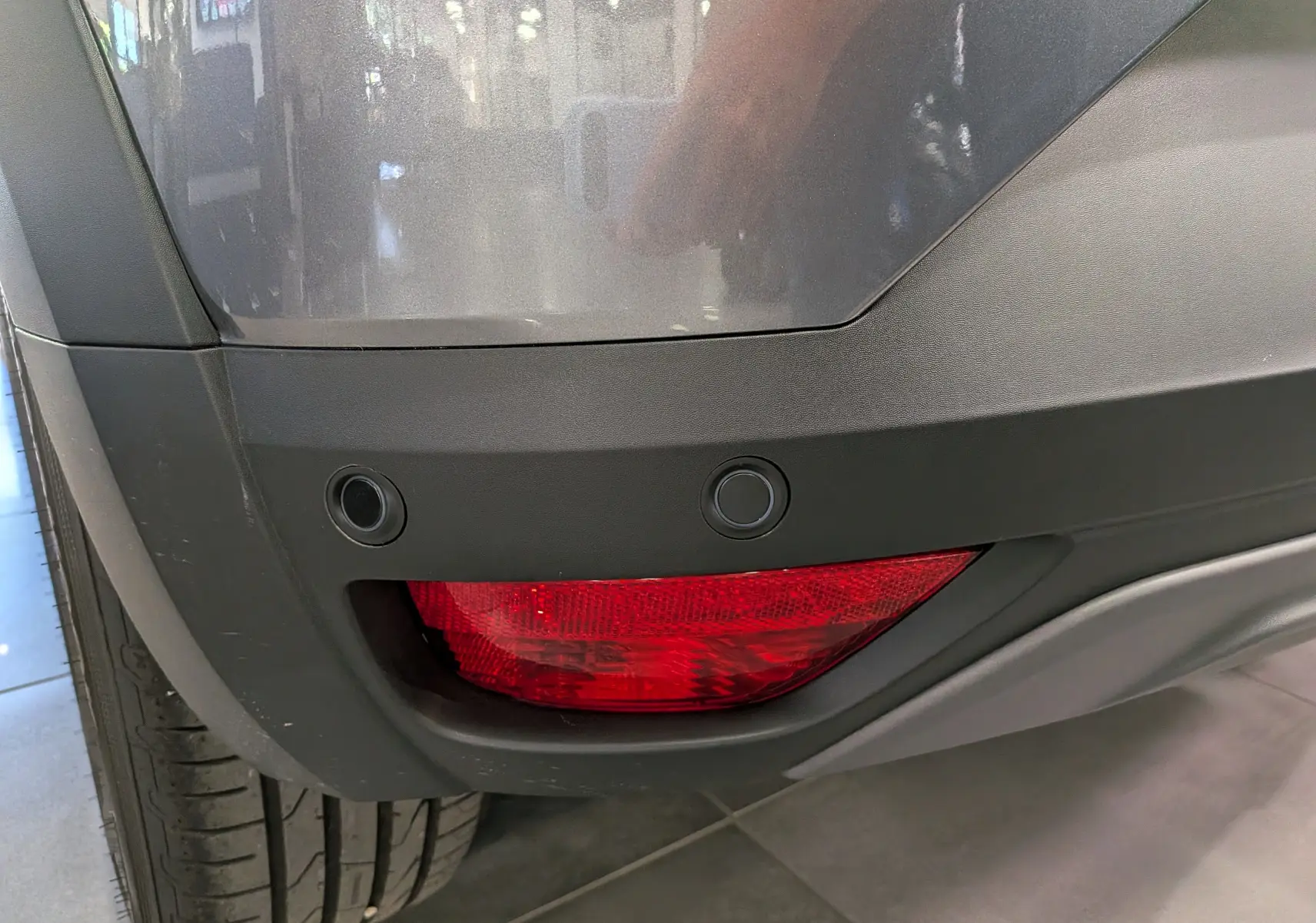 Gros plan sur le feu arrière droit rouge et le pare-chocs gris schiste du Dacia Sandero Stepway TCe 110 CH Extreme 2025.