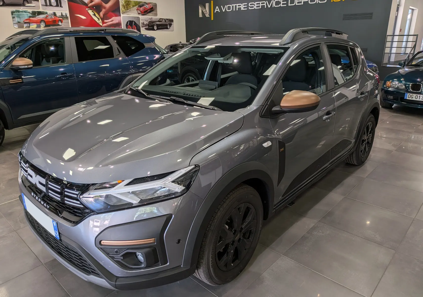 Vue 3/4 avant droit d'une Dacia Sandero Stepway TCe 110 Gris Schiste avec rétroviseurs bronze et jantes noires.