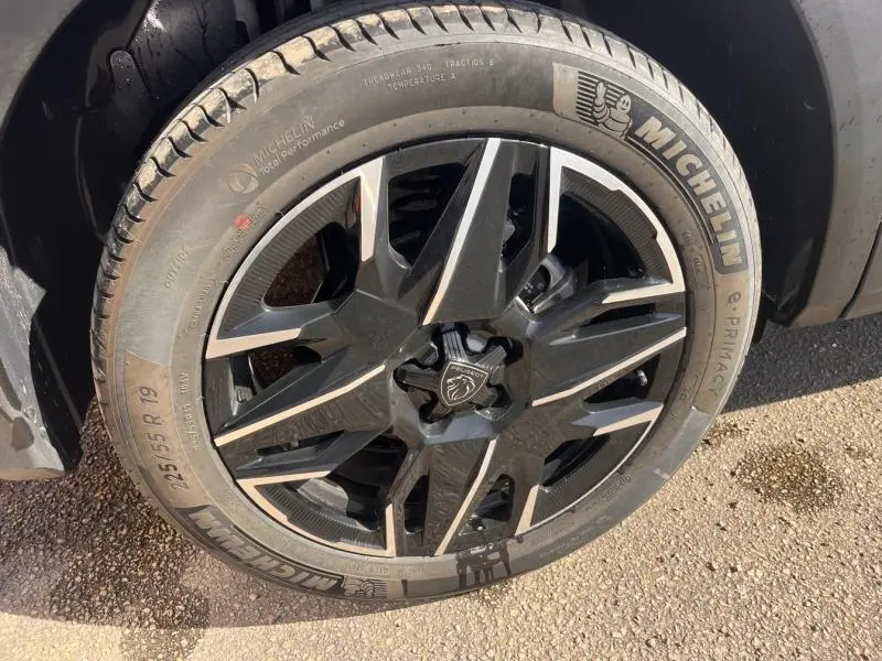 Gros plan sur la jante alu noire et argentée du Peugeot 3008 gris Artense avec pneu Michelin visible au sol.