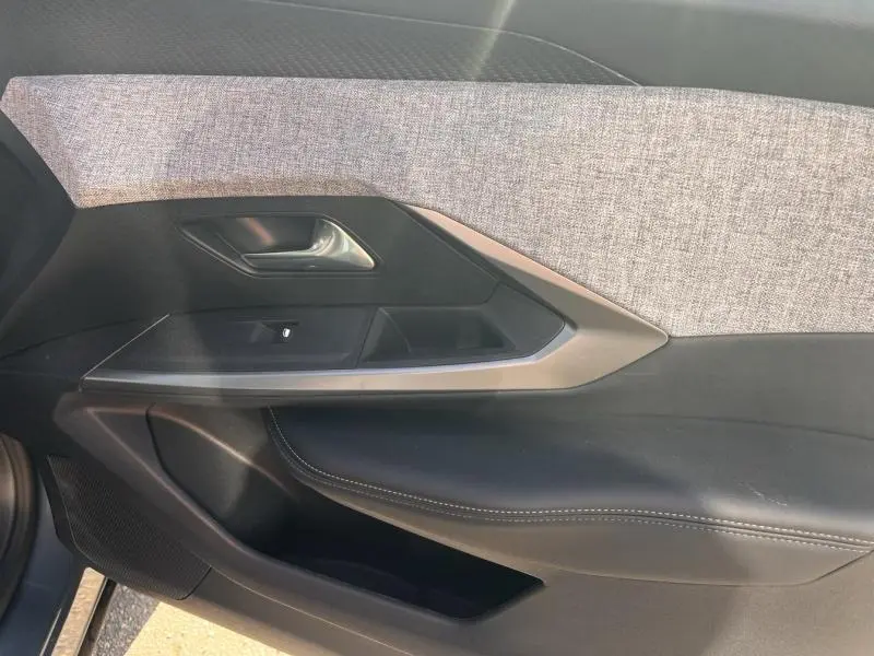 Vue latérale du panneau de porte côté gauche du Peugeot 3008 gris Artense avec tissu clair et garniture noire en cuir.