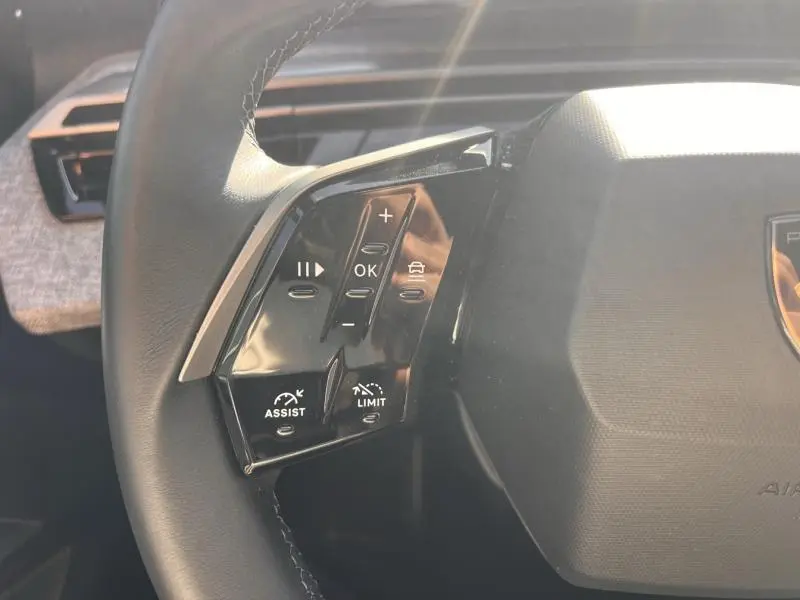 Gros plan sur les commandes multifonctions à gauche du volant cuir du Peugeot 3008 gris Artense, version 2025.