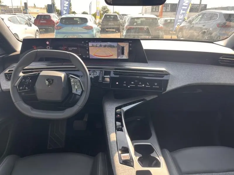 Vue intérieure avant du Peugeot 3008 1.2 Hybrid 145ch Allure e-DCS6 2025, tableau de bord moderne avec écran tactile et volant cuir.