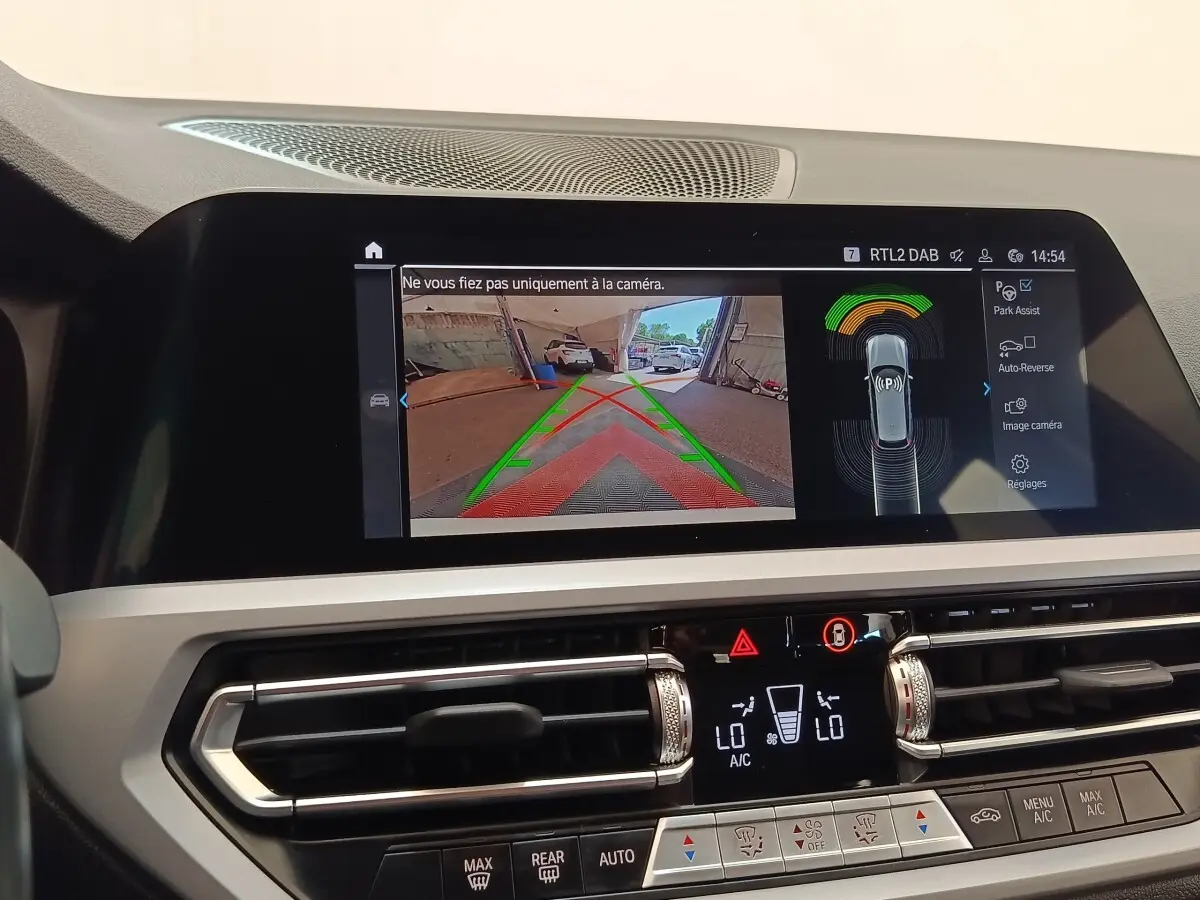 Écran tactile intérieur montrant la caméra de recul et l’aide au stationnement dans une BMW Série 3 blanche.