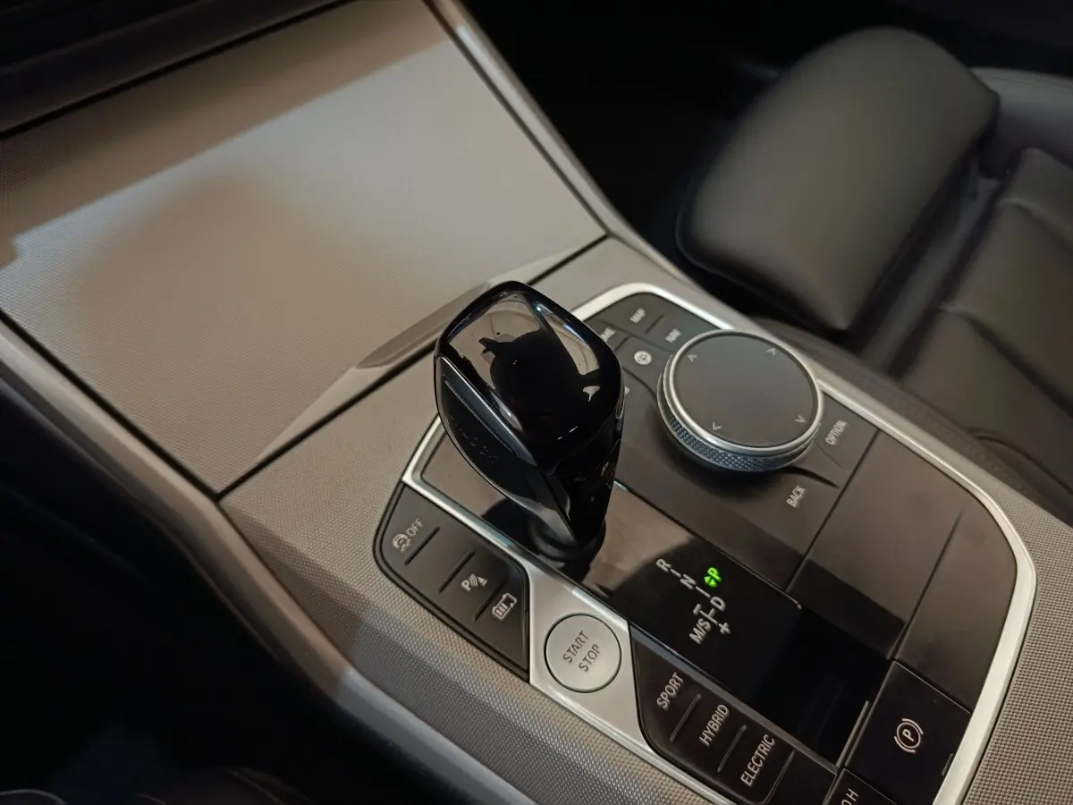 Gros plan sur la console centrale noire et argentée avec levier de vitesses et bouton démarrage d’une BMW Série 3 blanche.